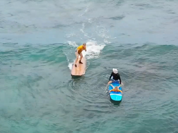 Surfing student and instructor catching a wave